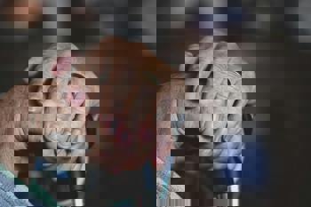 Elderly hands clasped gently over a cane handle