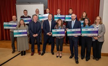 A group of people stood on a stage holding boards with pledges